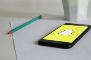  Snapchat logo on a smartphone next to a pen