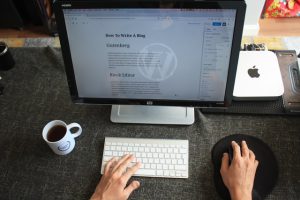  Person writing a blog on their computer with a coffee mug next to it